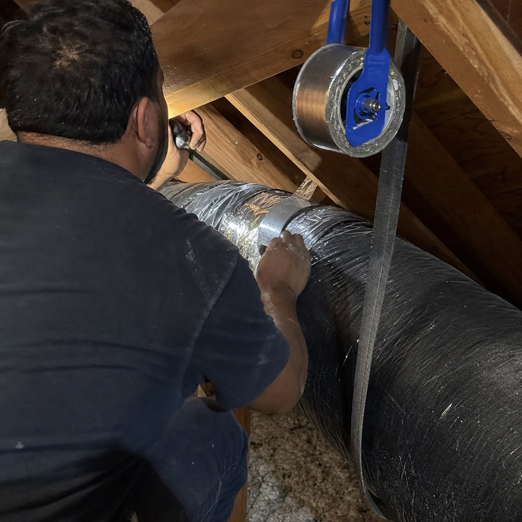 Technician performing professional HVAC duct repair and sealing in an attic